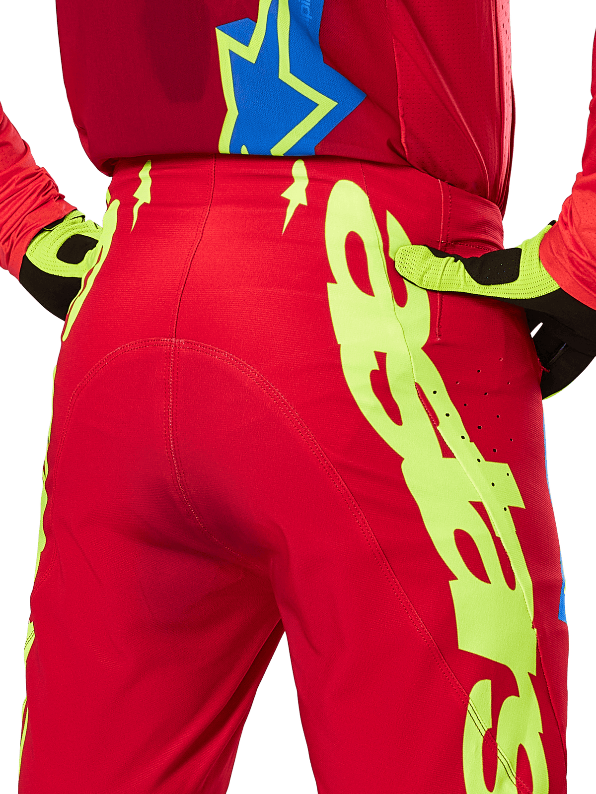 Alpinestars Pantaloni Supertech Maker 2025, pantaloni da motocross, rosso acceso e giallo fluo, primo piano posteriore con grafica giallo neon, indossati con maglia rossa coordinata e guanti gialli e neri