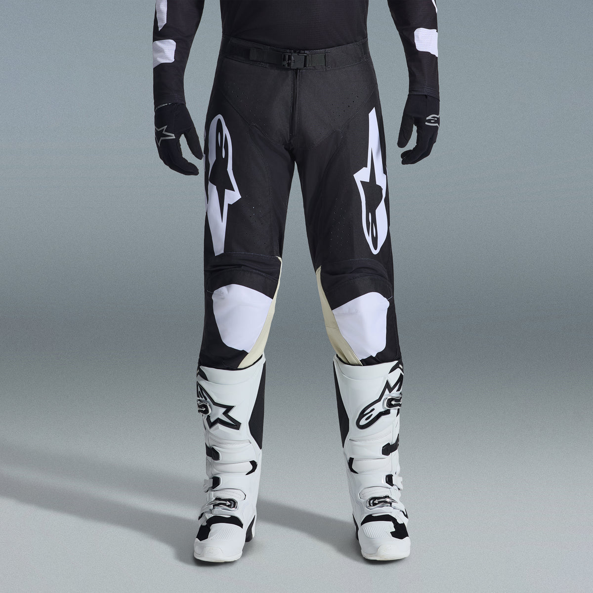 Alpinestars 2026 Racer Air Riway Gear Set, pantaloni da motocross neri e bianchi con pannelli interni alle ginocchia beige, abbinati a stivali da corsa bianchi e guanti neri, abbigliamento da corsa off-road leggero e ventilato