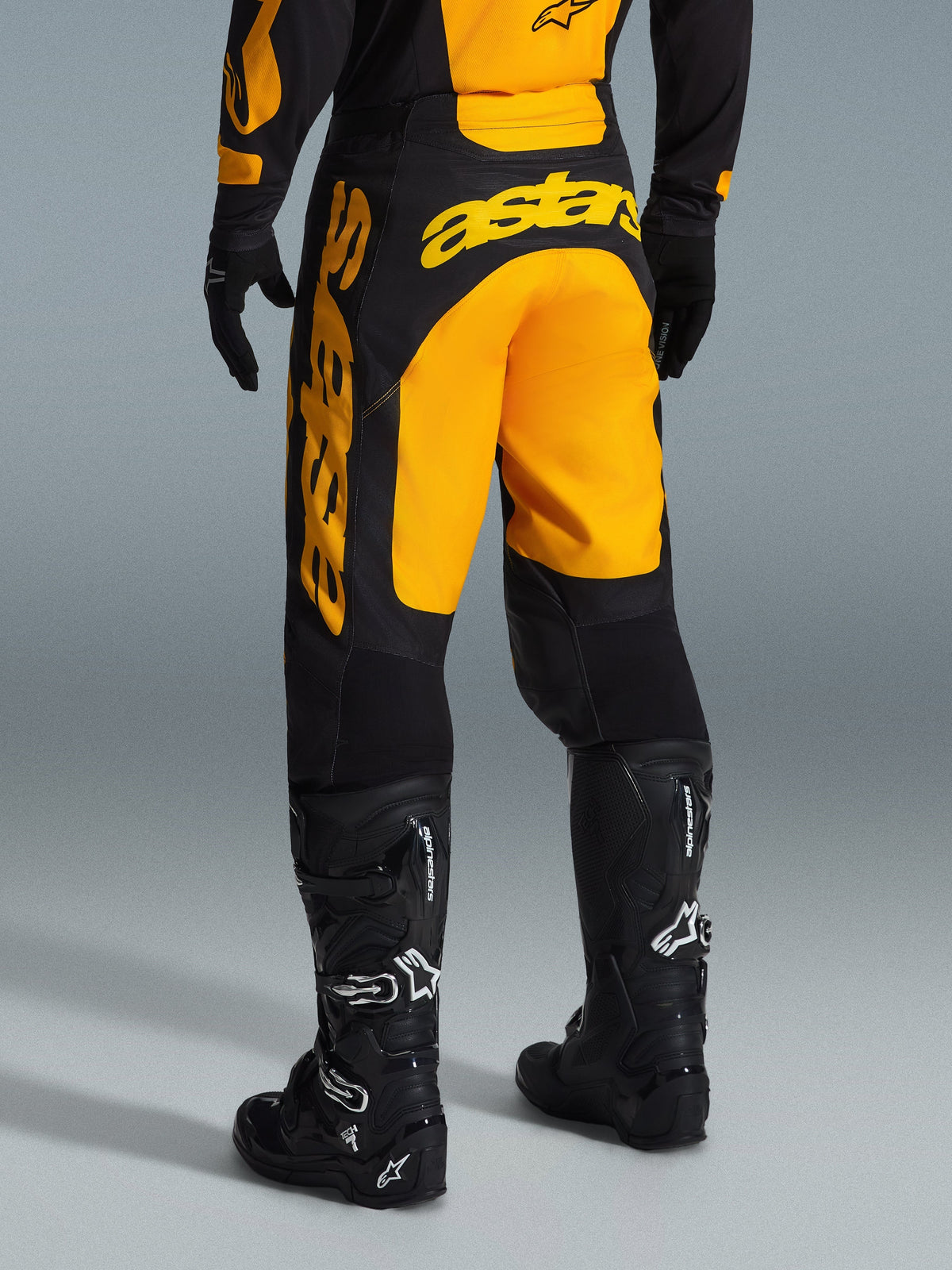 Alpinestars 2026 Racer Riway Pants, pantaloni da motocross, giallo e nero, vista posteriore che mostra il marchio astars giallo sulla seduta e sulla gamba, abbinati a stivali e guanti da motocross neri