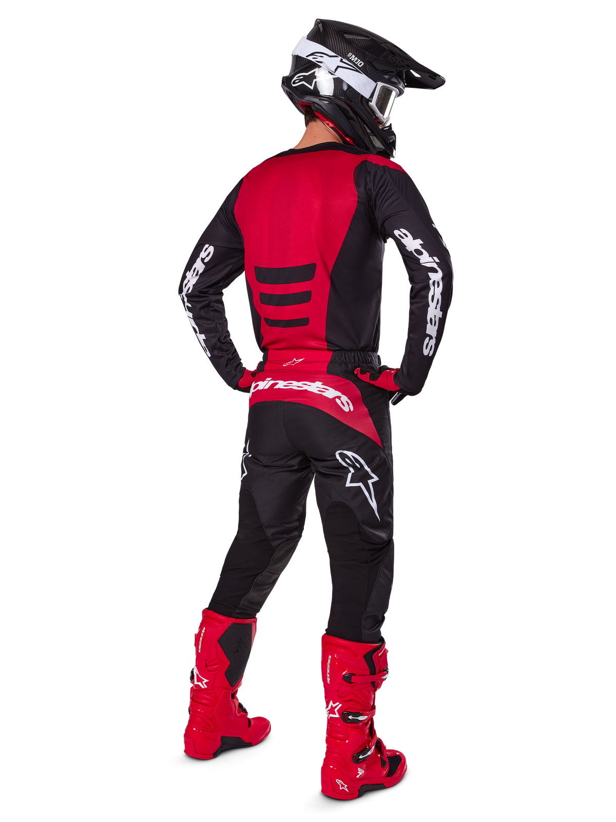 Pilota di motocross con il Set Gear Alpinestars 2025 Fluid Haul visto da dietro, maglia rossa e nera con logo bianco, pantaloni neri coordinati con accenti rossi, stivali rosso acceso e casco nero con occhiali bianchi, outfit completo coordinato per gare off-road