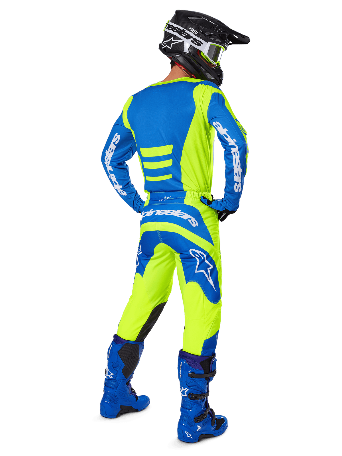 Pilota di motocross visto da dietro che indossa i pantaloni Alpinestars 2025 Fluid Haul e la maglia coordinata in Giallo Fluo e Blu, abbinati a stivali blu e casco nero Alpinestars, equipaggiamento professionale per gare fuoristrada