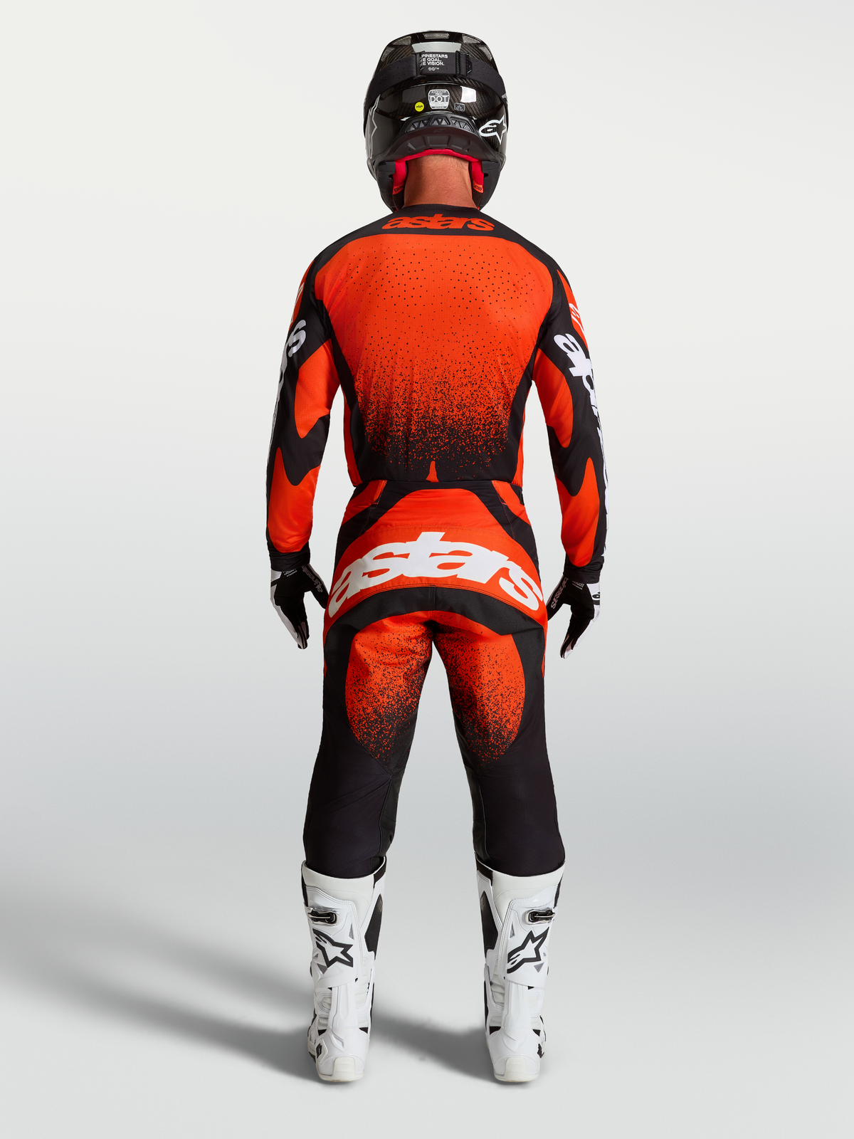 Alpinestars pantaloni Techstar Swan da motocross per uomo, rossi e neri, vista posteriore con stivali racing bianchi.