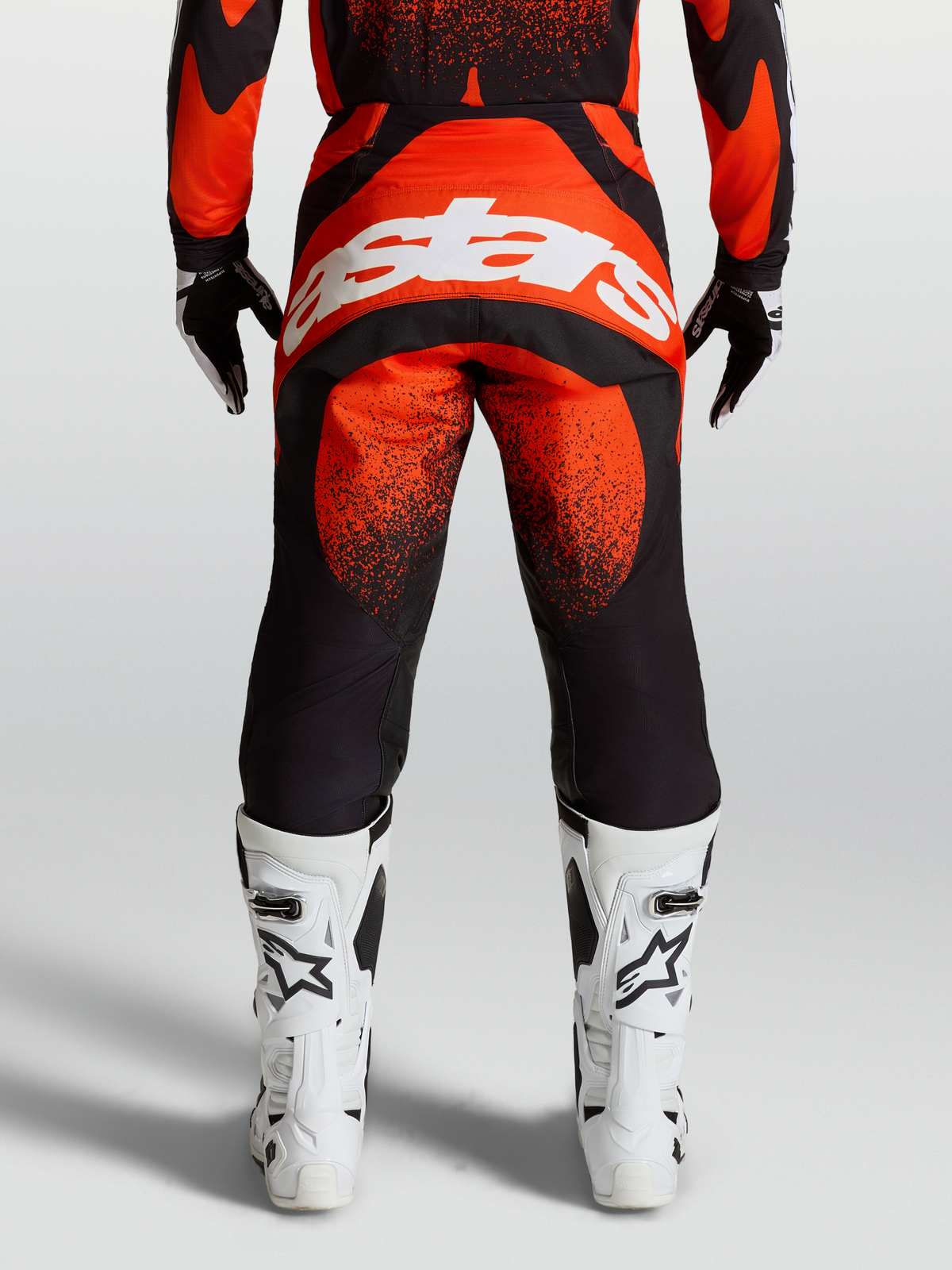 Alpinestars Pantaloni Techstar Swan, pantaloni da motocross rossi e neri, vista posteriore con logo bianco e stivali bianchi