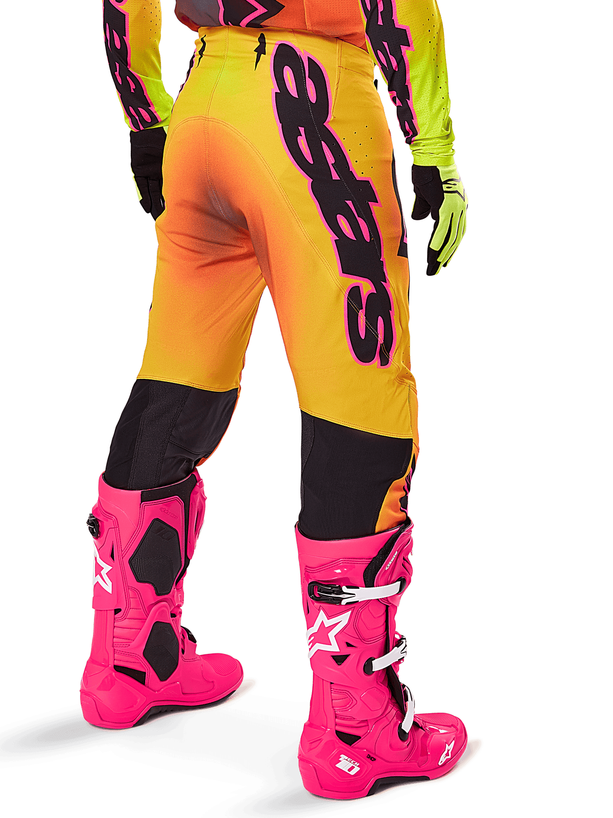 Alpinestars 2025 Supertech Lipan Gear Set, vista posteriore di pantaloni da motocross con sfumatura giallo e arancione e branding nero audace, abbinati a stivali Tech 10 rosa acceso e guanti gialli, attrezzatura professionale per corse fuoristrada