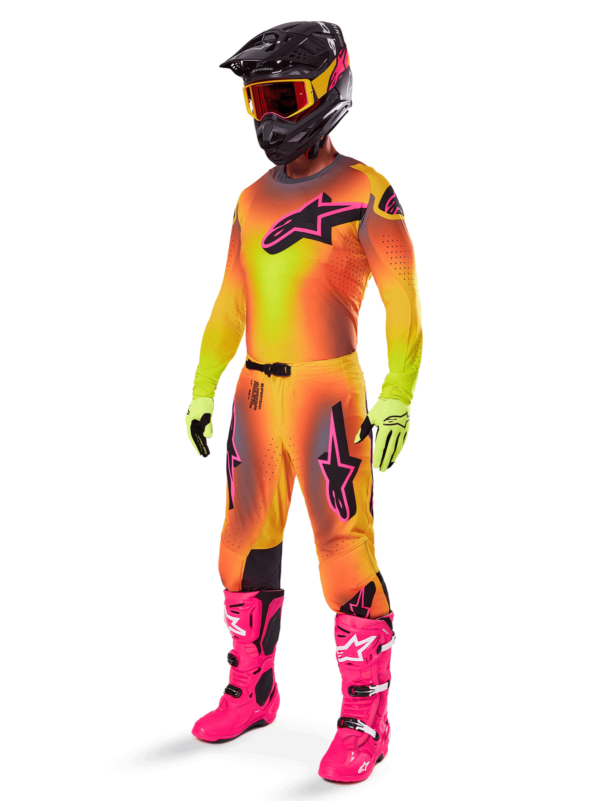 Alpinestars 2025 Supertech Lipan Pants, pantaloni da motocross, giallo e rosa, indossati come parte di un set completo con maglia sfumata coordinata, stivali rosa acceso, guanti gialli e casco nero, con loghi neri audaci e vestibilità atletica per corse fuoristrada
