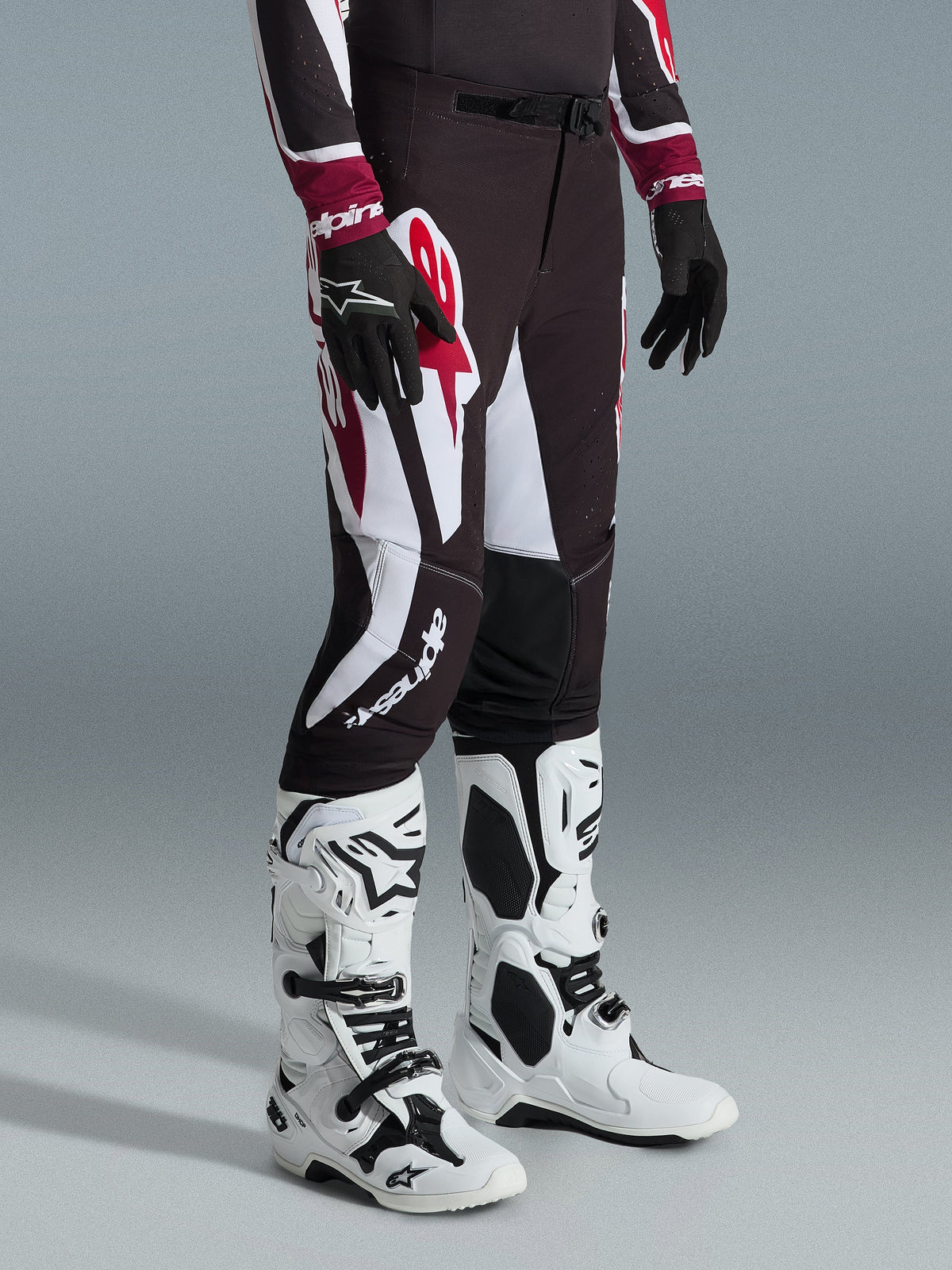 Alpinestars 2026 Supertech AFD Vista Pants, pantaloni da motocross, nero, rosso e bianco, indossati con stivali da motocross bianchi e neri e guanti neri, con ampie grafiche bianche e rosse, design con vestibilità atletica da gara