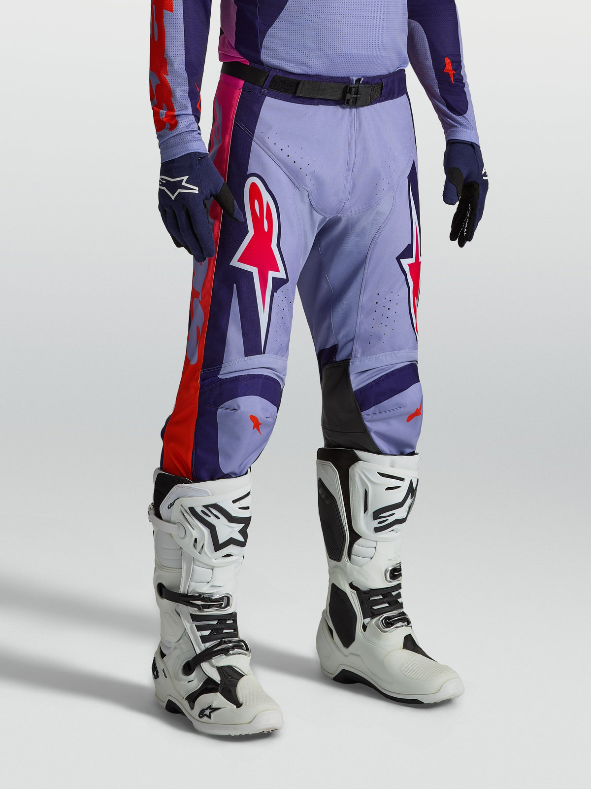 Alpinestars Pantaloni Racer Air Hunt, pantaloni da motocross da uomo viola e rosa ventilati, mostrati con stivali bianchi