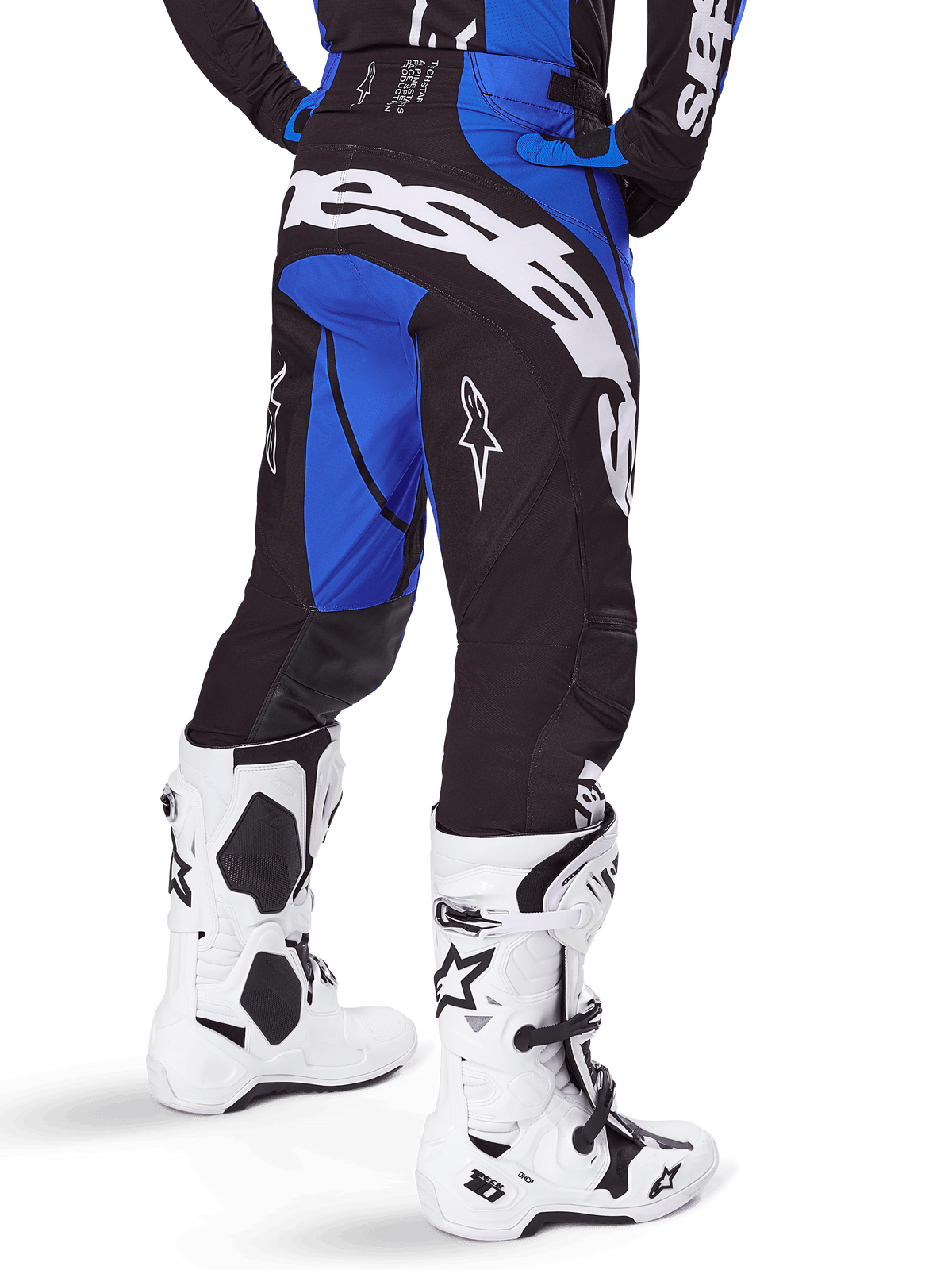Alpinestars 2025 Techstar Dreem Pants, pantaloni da motocross, nero e blu, vista posteriore con audace marchio Alpinestars bianco sulla seduta, indossati con stivali da motocross bianchi e neri e maglia blu coordinata, vestibilità atletica per gare fuoristrada