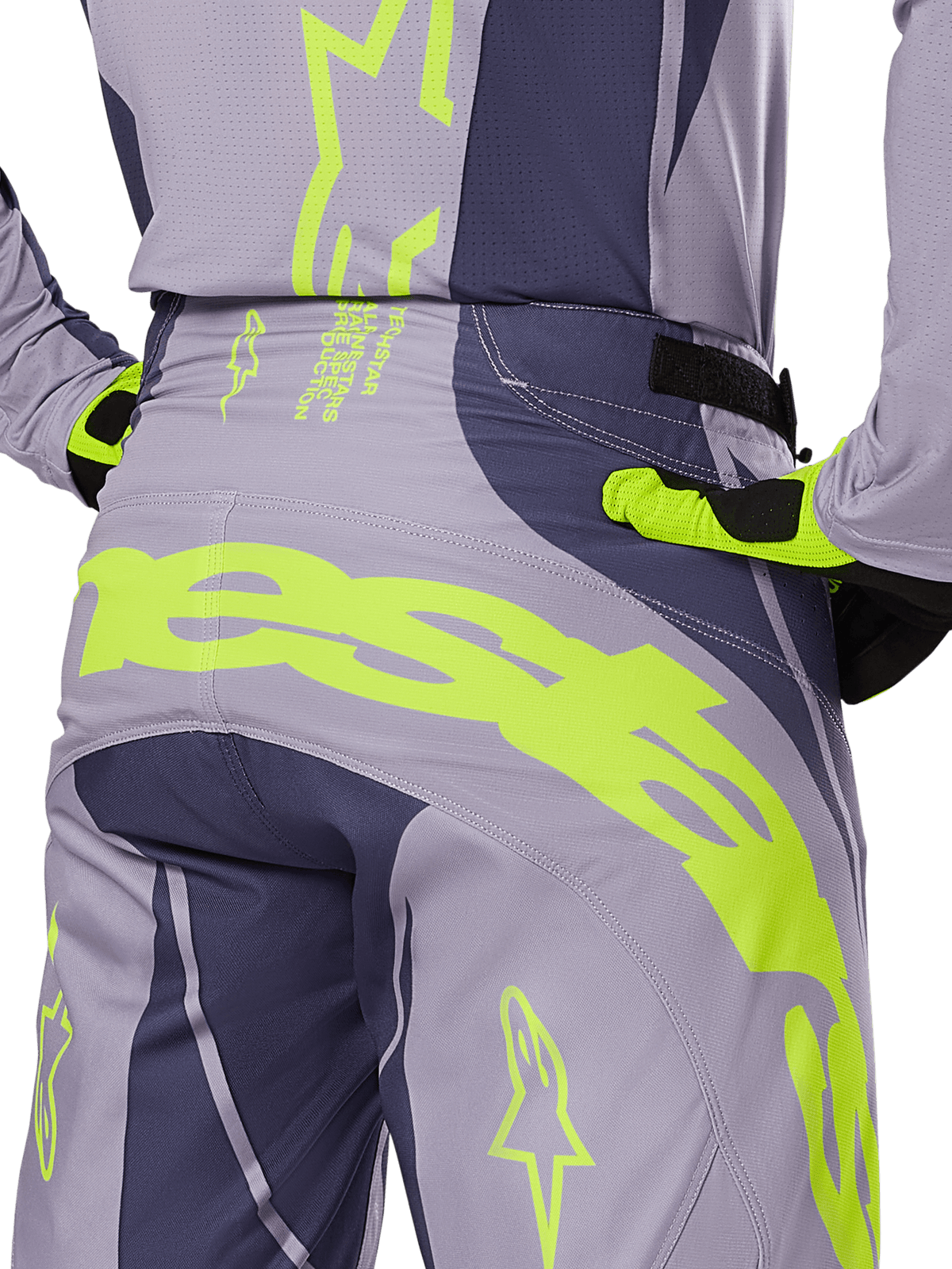 Alpinestars 2025 Techstar Dreem Pants, pantaloni da motocross, grigio e grigio scuro con accenti giallo fluorescente, vista posteriore con marchio Alpinestars sul carré, indossati con maglia e guanti coordinati, progettati per gare fuoristrada