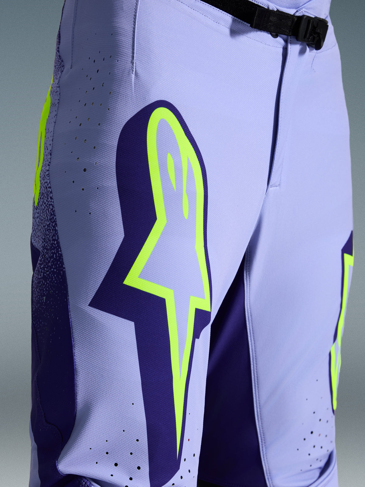 Alpinestars Pantaloni Supertech Scenz 2026, pantaloni da motocross, viola e giallo fluo, primo piano con grande logo giallo sulla coscia, perforazioni tagliate al laser per la ventilazione e fibbia magnetica in vita, abbigliamento off-road con vestibilità atletica