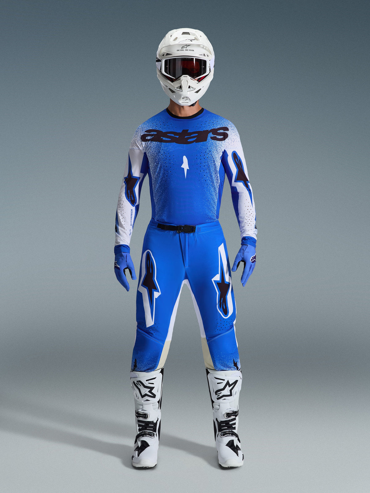 Abbigliamento completo da motocross Alpinestars, maglia blu e bianca con marchio astars nero, pantaloni Supertech Scenz 2026 in Ucla Blue White con grandi loghi a stella, casco bianco, guanti blu e stivali bianchi, outfit da gara atletico coordinato