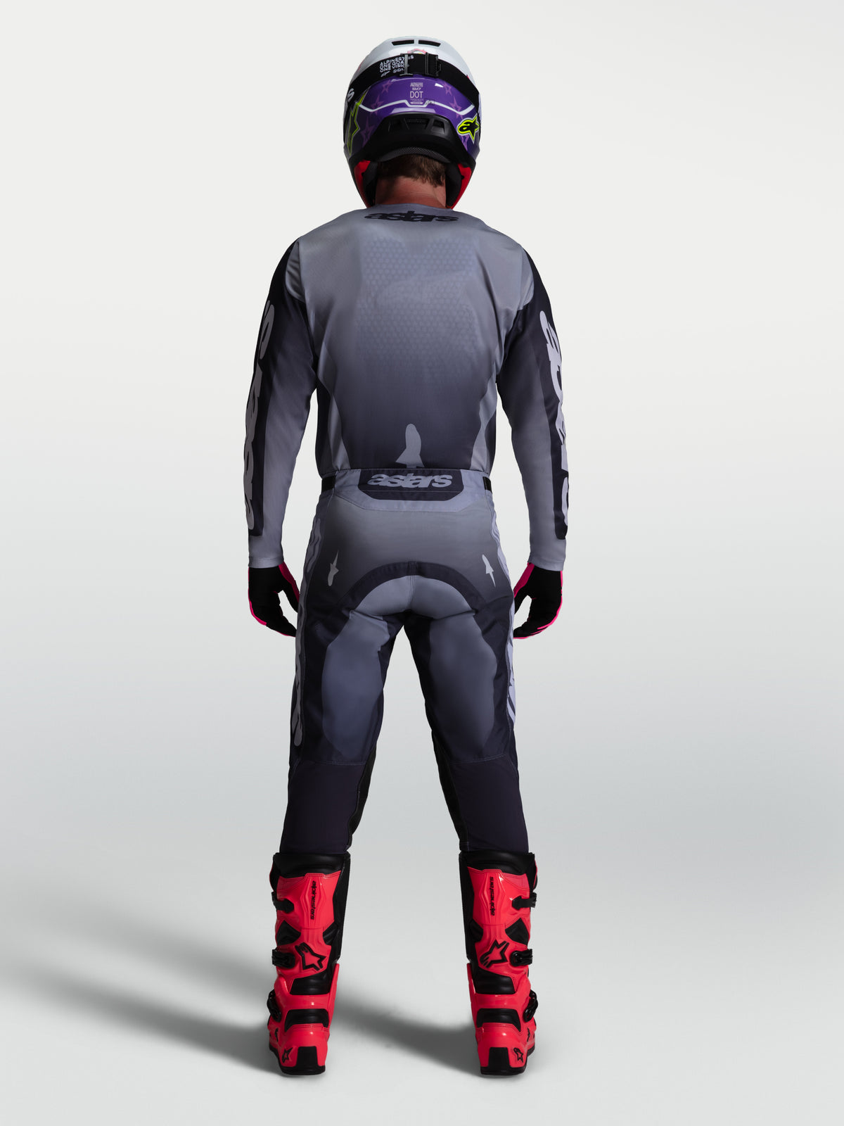 Alpinestars Pantaloni Racer Amber, pantaloni da motocross da uomo, grigio e lilla chiaro, vista posteriore con stivali rossi, abbigliamento tecnico off-road