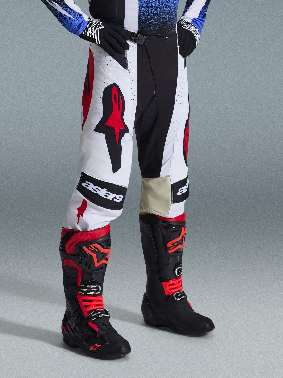 Alpinestars 2026 Techstar Knif Pants, pantaloni da motocross, nero, bianco e rosso, indossati con stivali da motocross neri e rossi, con vistoso branding Astars sulle cosce, vestibilità atletica racing e costruzione multi-pannello resistente per gare off-road