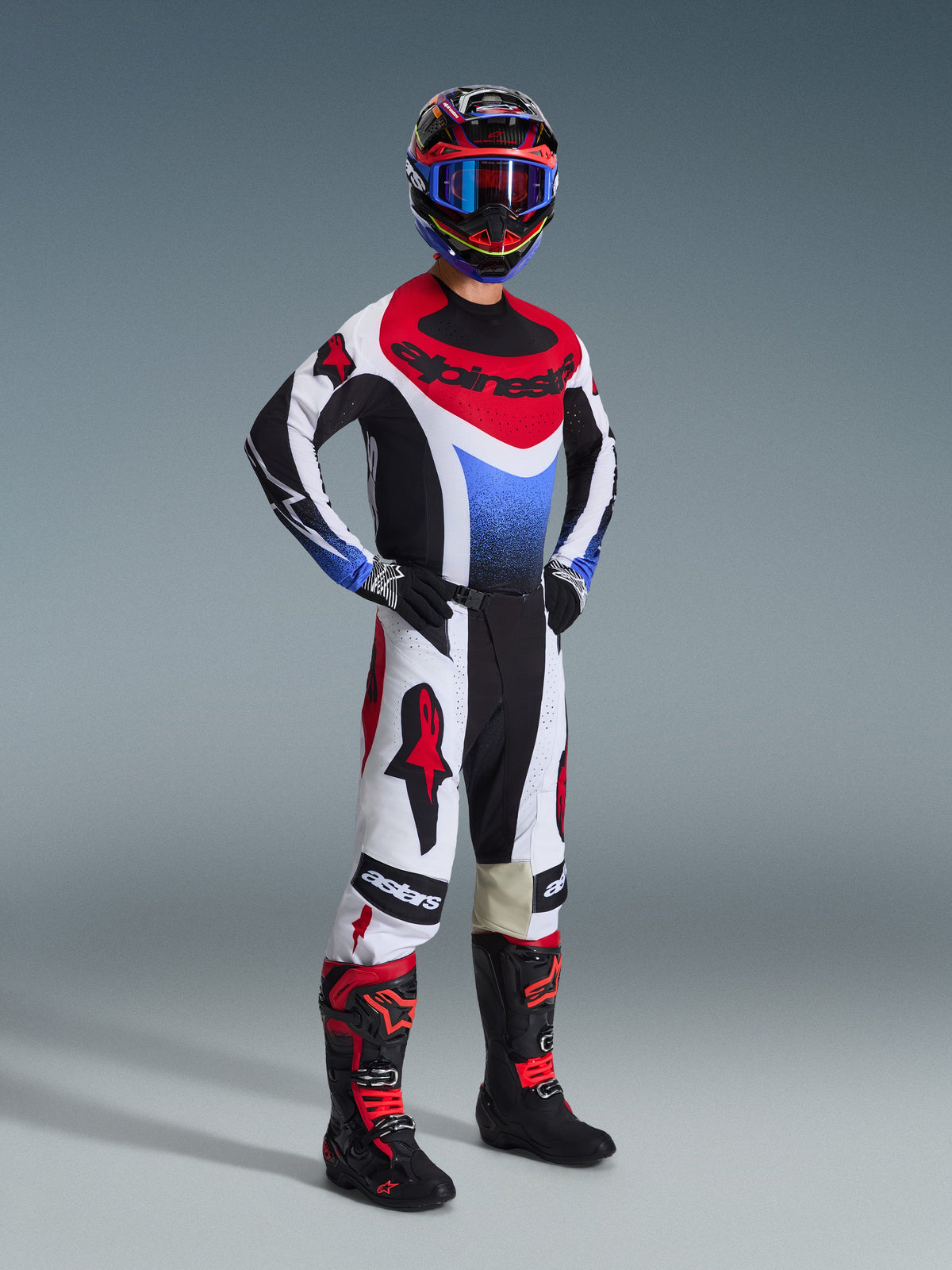 Alpinestars Techstar Knif Pants 2026, pantaloni da motocross, nero, bianco e rosso, indossati da un pilota con equipaggiamento da gara completo, maglia e stivali coordinati, con loghi Alpinestars rossi su pannelli bianchi e vestibilità atletica orientata alle prestazioni.