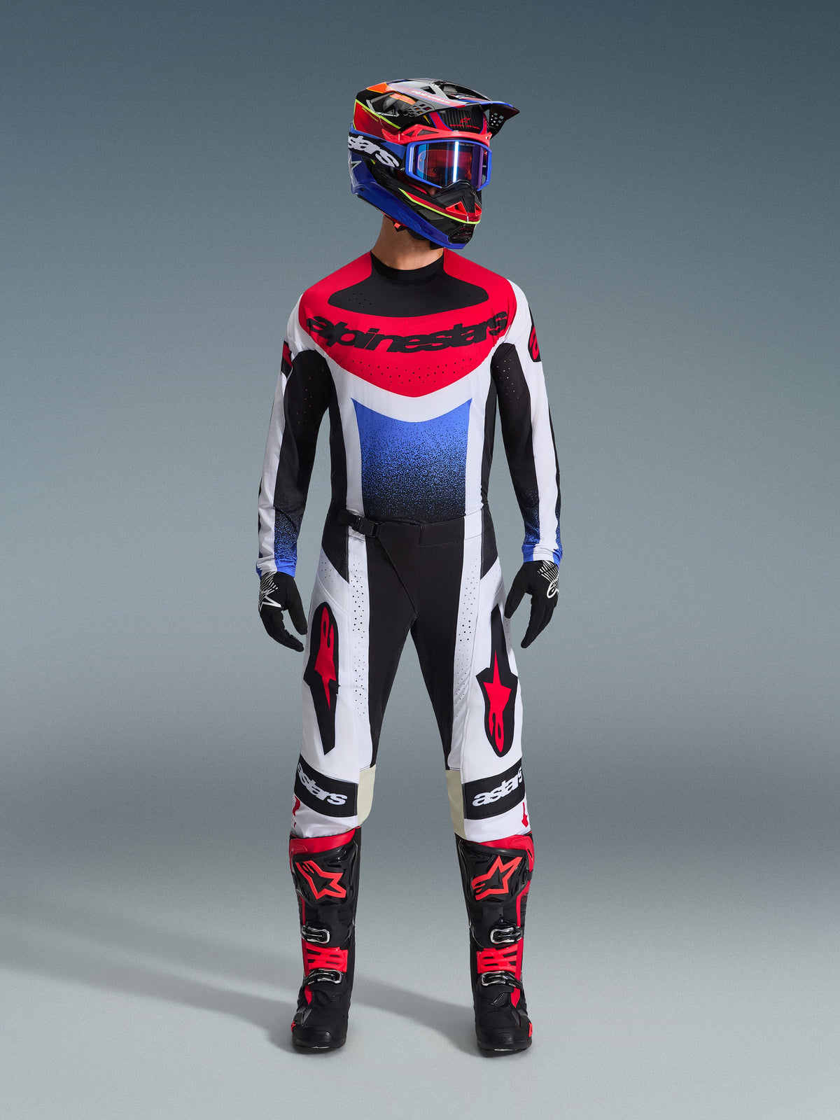 Pantaloni Alpinestars Techstar Knif 2026, pantaloni da motocross, nero, bianco e rosso, indossati come parte di un set da gara completo con maglia e casco coordinati, con loghi a stella rossi sulle cosce e vestibilità atletica per corse off-road