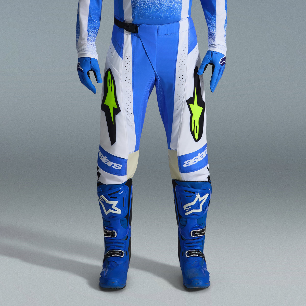 Alpinestars 2026 Techstar Knif Gear Set, pantaloni da motocross blu e bianchi con loghi giallo fluorescente, stivali e guanti blu coordinati, abbigliamento sportivo professionale per competizioni fuoristrada