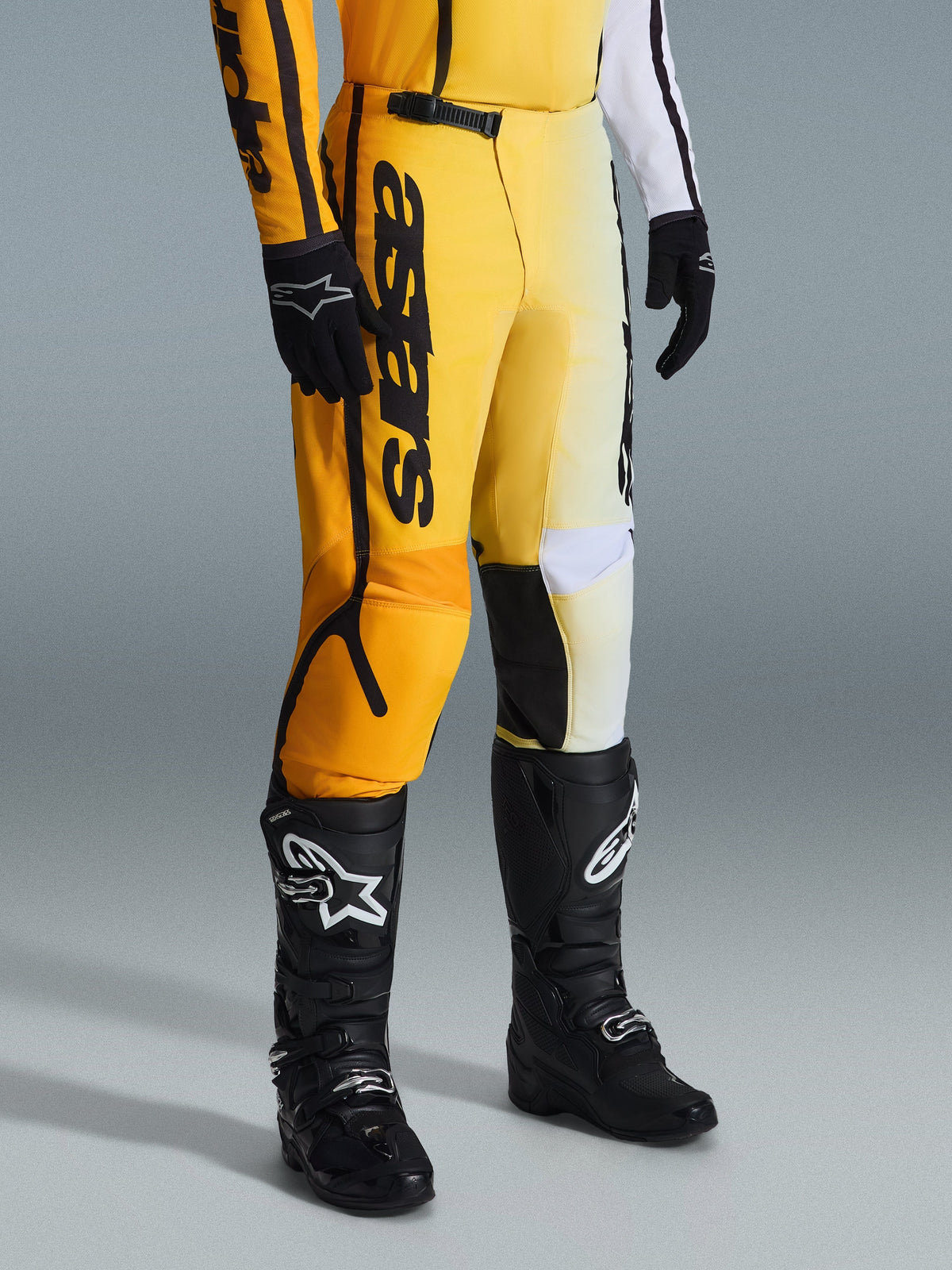 Alpinestars 2026 Fluid Apex Pants, pantaloni da motocross, giallo e nero, indossati con stivali e guanti neri, caratterizzati dal vistoso logo 'astars' sulla coscia, design ergonomico con pannelli rinforzati, materiale resistente per la guida off-road