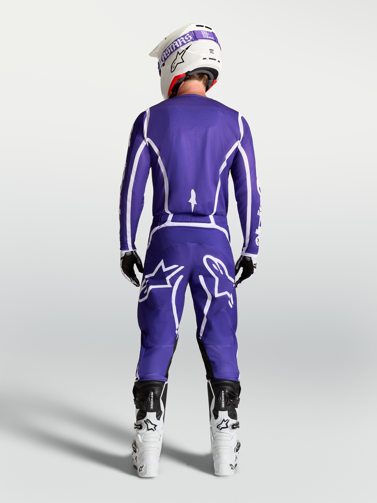 Alpinestars Pantaloni Fluid Apex V2, abbigliamento motocross da uomo, blu e bianco, vista posteriore su modello con stivali racing bianchi