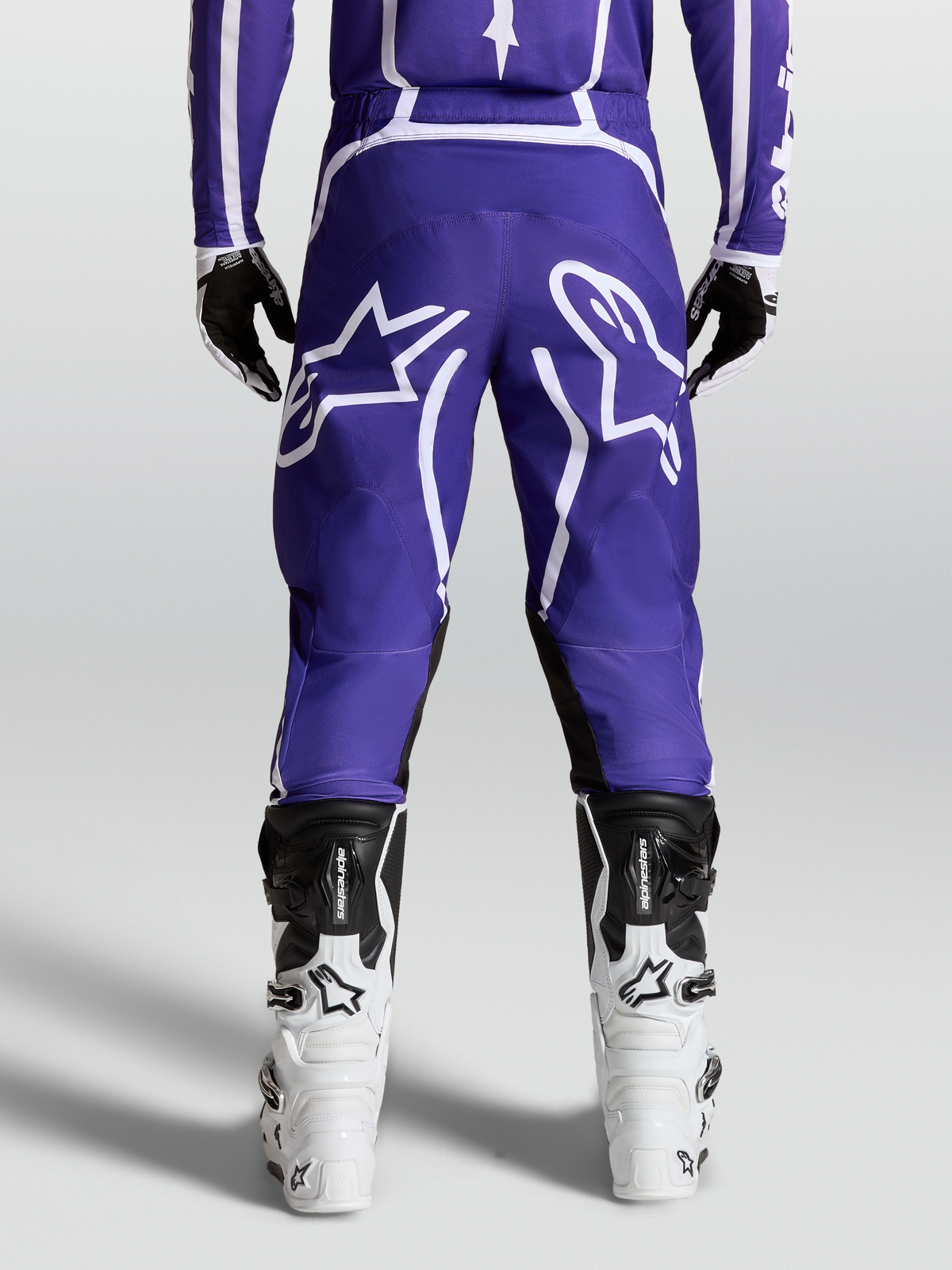 Alpinestars Pantaloni Fluid Apex V2, pantaloni motocross da uomo, blu scuro e bianchi, vista posteriore con stivali, in poliestere 600D resistente