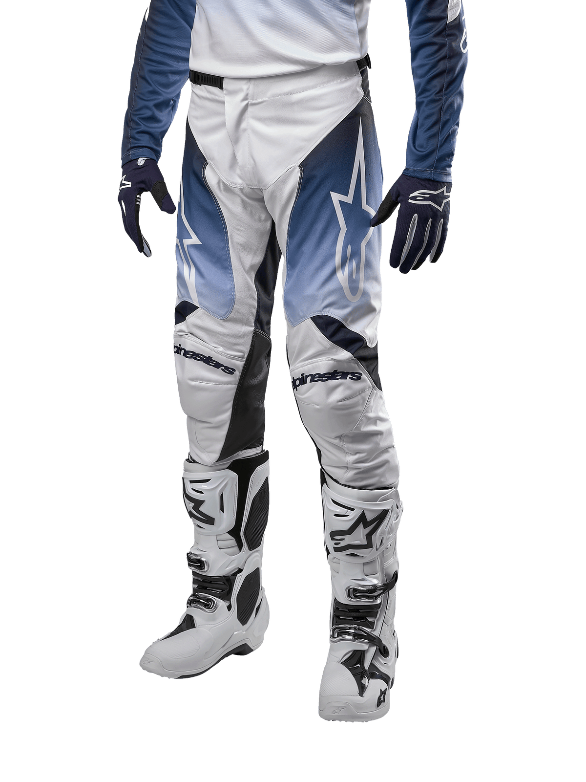 Alpinestars 2024 Racer Hoen Pants, pantaloni da motocross, bianco con sezioni blu navy e azzurro, logo a stella bianco, indossati con stivali bianchi e neri e guanti blu, abbigliamento protettivo per fuoristrada