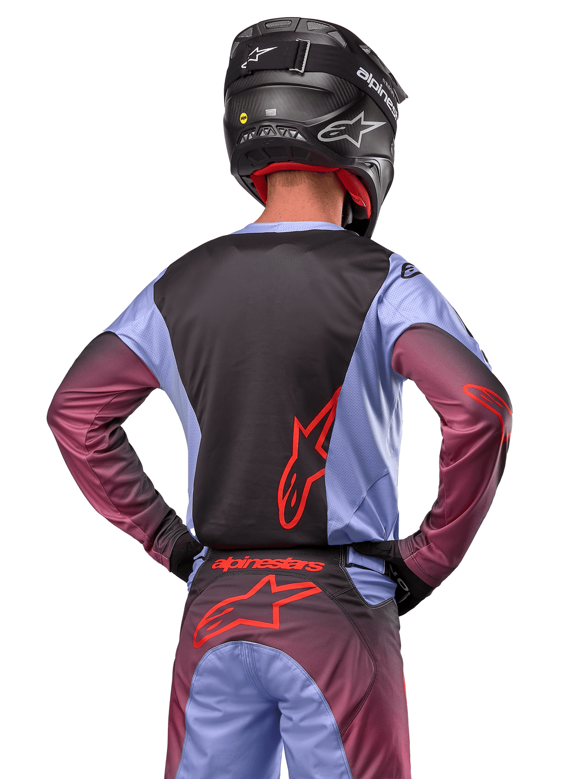 Pilota di motocross visto di spalle con abbigliamento Alpinestars Racer Hoen 2024, maglia Lavan Purple e nera con logo rosso, pantaloni coordinati con dettagli rossi, casco nero, completo coordinato per corse fuoristrada