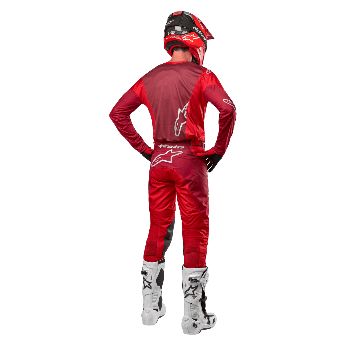 Alpinestars 2024 Racer Hoen Pants e maglia coordinata in Mars Red Burgundy, vista posteriore di un pilota di motocross in equipaggiamento completo con casco rosso e stivali bianchi, che mostra la vestibilità atletica e il branding per il racing fuoristrada.