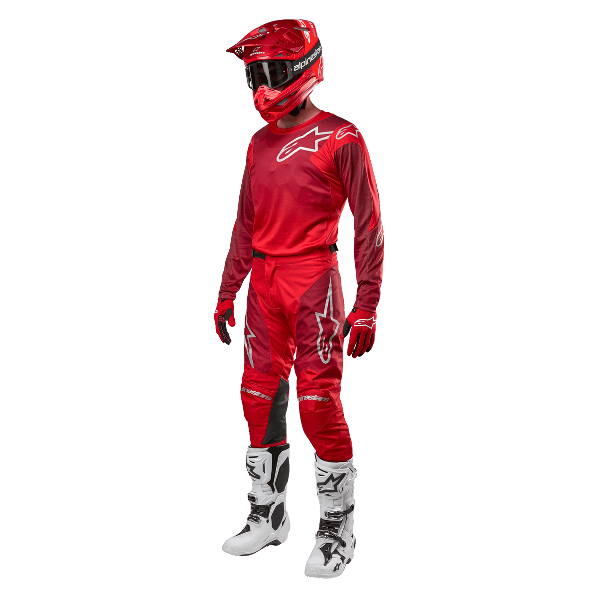 Pilota di motocross con equipaggiamento completo da gara, pantaloni e maglia Alpinestars Racer Hoen 2024 in Mars Red Burgundy, casco rosso, guanti rossi e stivali bianchi e neri, completo coordinato per il fuoristrada