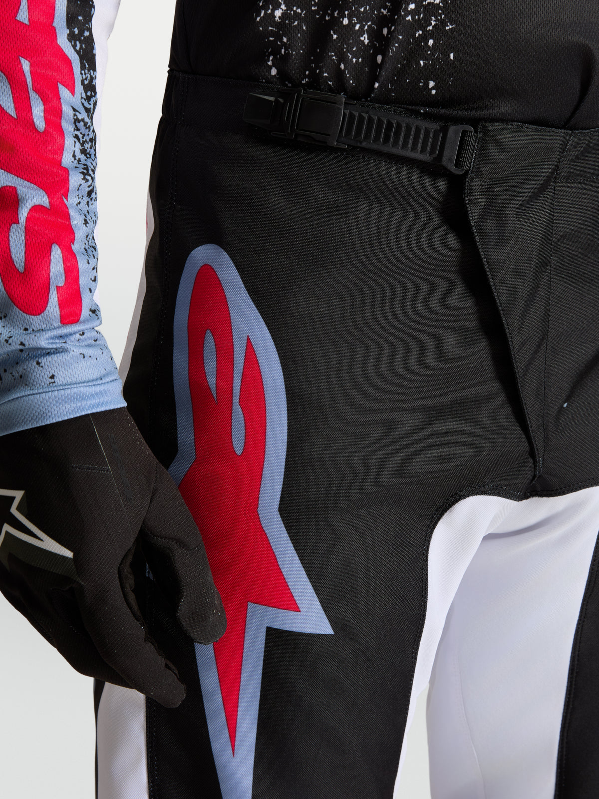 Alpinestars Pantaloni Fluid Drag, pantaloni da motocross neri e rossi con chiusura a cricchetto e logo grafico.