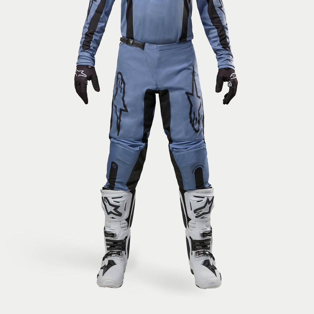 Alpinestars Pantaloni Fluid Lurv 2024, pantaloni da motocross, azzurro e nero, indossati con stivali da corsa bianchi e neri e guanti coordinati, con vistosi loghi a stella neri sulle cosce, design ergonomico per prestazioni off-road