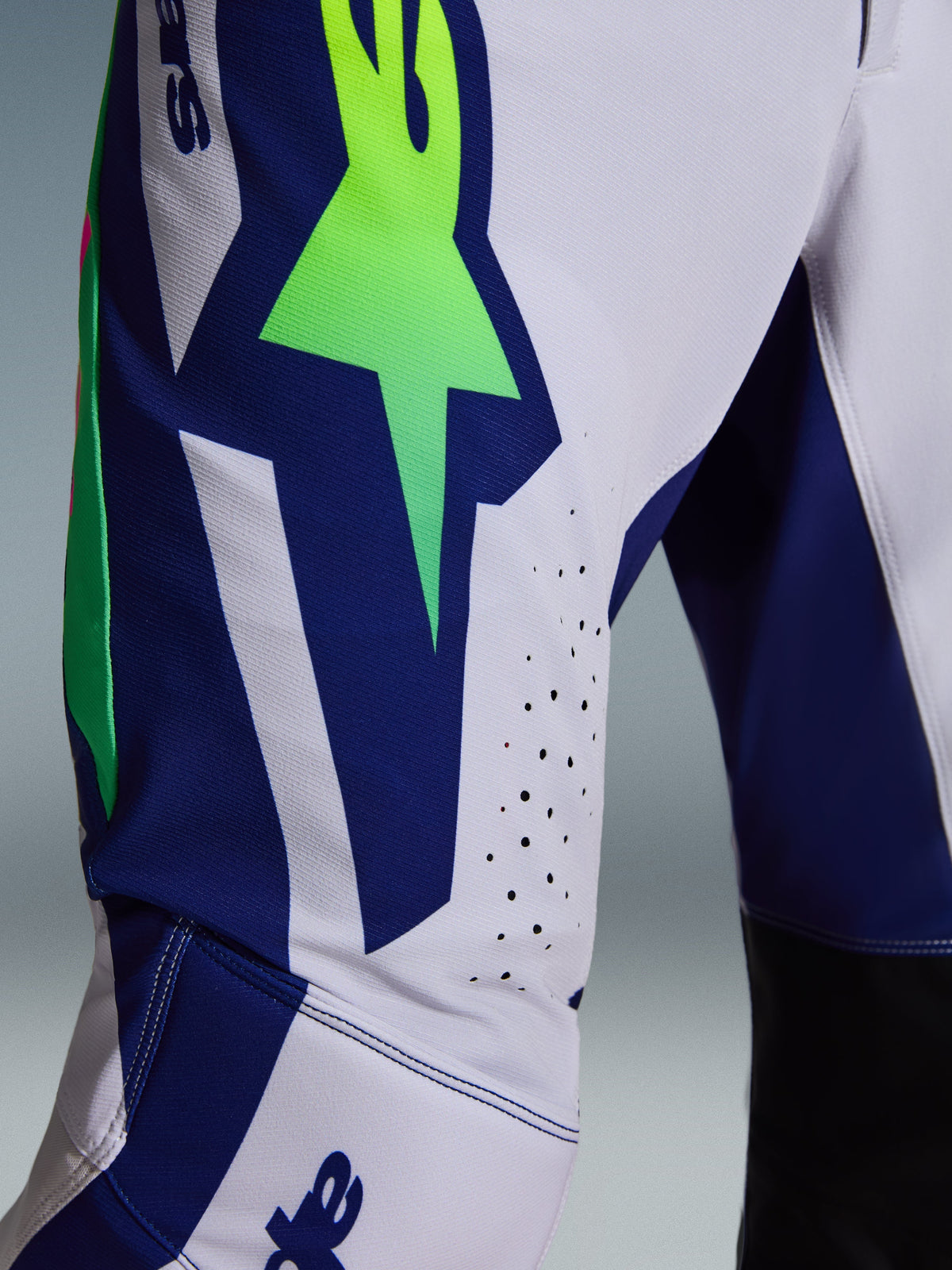 Alpinestars Supertech Vista Pants 2026, pantaloni da motocross, grigio chiaro con accenti giallo fluo e blu, vista ravvicinata della coscia con grande logo A-star, fori di ventilazione tagliati al laser e tessuto rip-stop elasticizzato.
