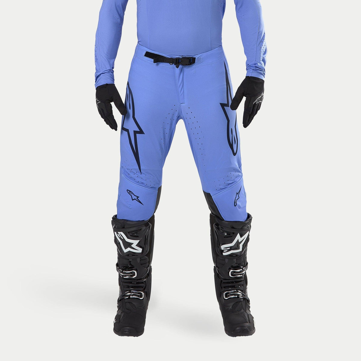 Alpinestars 2024 Supertech Dade Pants, pantaloni da motocross, azzurro, con grandi loghi Astars neri sulle cosce, fibbia nera in vita, indossati con stivali da motocross neri e maglia blu coordinata, abbigliamento professionale per corse fuoristrada