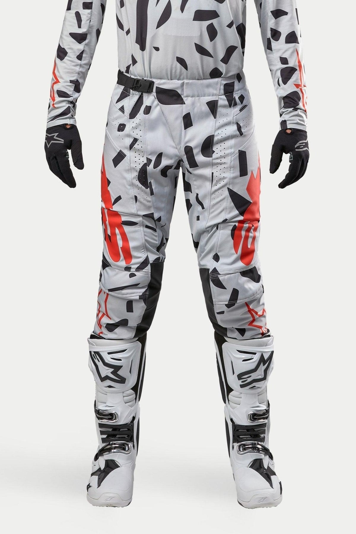 Alpinestars 2024 Techstar Rantera Pants, pantaloni da motocross, grigio mimetico Haze Gray, indossati con maglia coordinata, guanti neri e stivali bianchi, con motivo a macchie nere e logo Alpinestars rosso, design resistente per corse fuoristrada