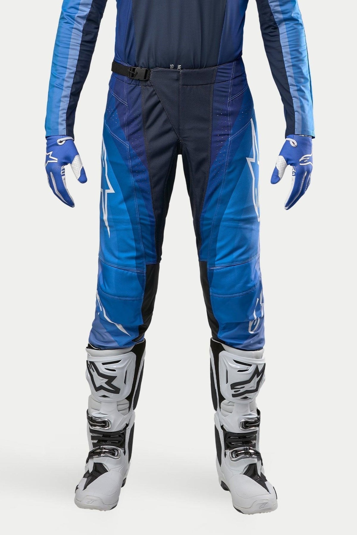Alpinestars Pantaloni Techstar Pneuma 2024, pantaloni da motocross, blu navy scuro e azzurro, indossati con maglia blu coordinata e stivali bianchi, con logo Alpinestars bianco e chiusura con fibbia magnetica, progettati per prestazioni professionali fuoristrada
