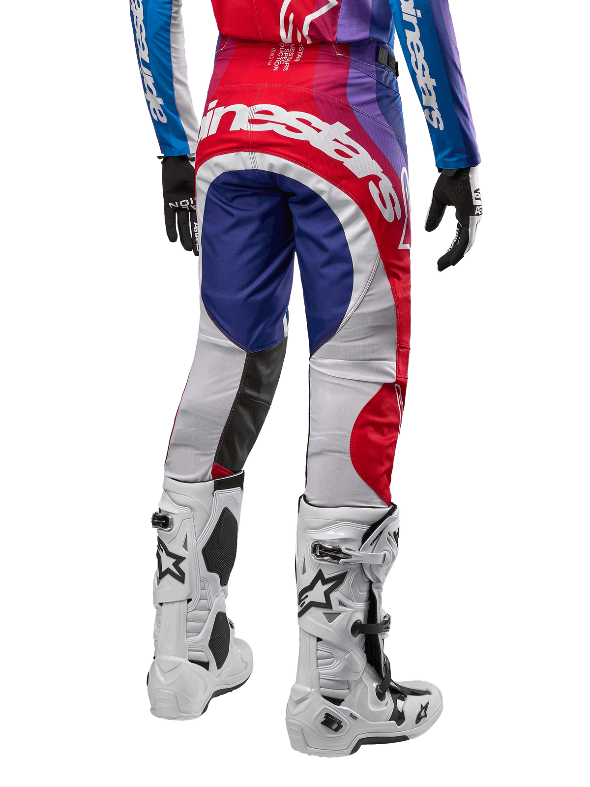 Alpinestars Pantaloni Techstar Pneuma 2024, pantaloni da motocross, Blu Mars Rosso Bianco, vista posteriore indossati con maglia coordinata e stivali bianchi, con logo bianco sulla seduta e pannelli multicolore, abbigliamento professionale da motocross