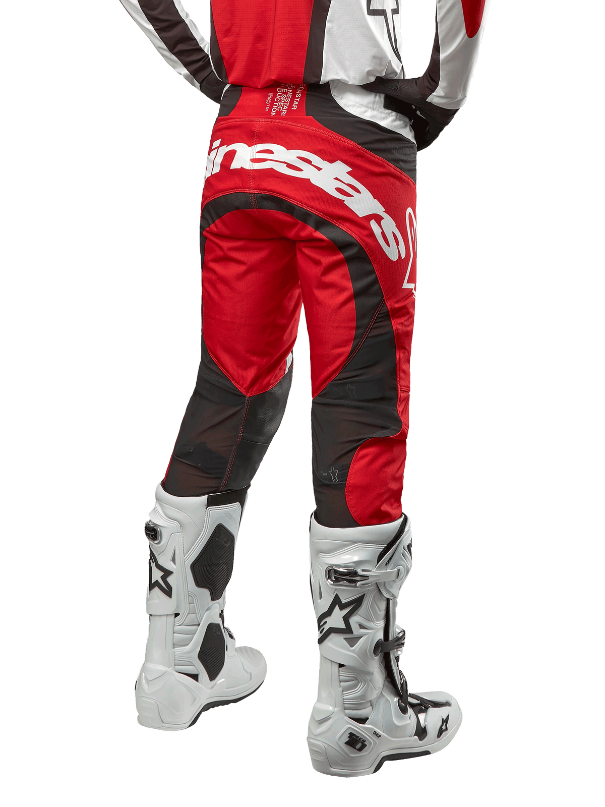 Alpinestars 2024 Techstar Ocuri Pants, pantaloni da motocross, Mars Red, bianco e nero, vista posteriore con grande logo Alpinestars bianco sulla seduta, pannelli di ventilazione in mesh nero, indossati con stivali da motocross bianchi e neri, design atletico race-fit per la guida off-road