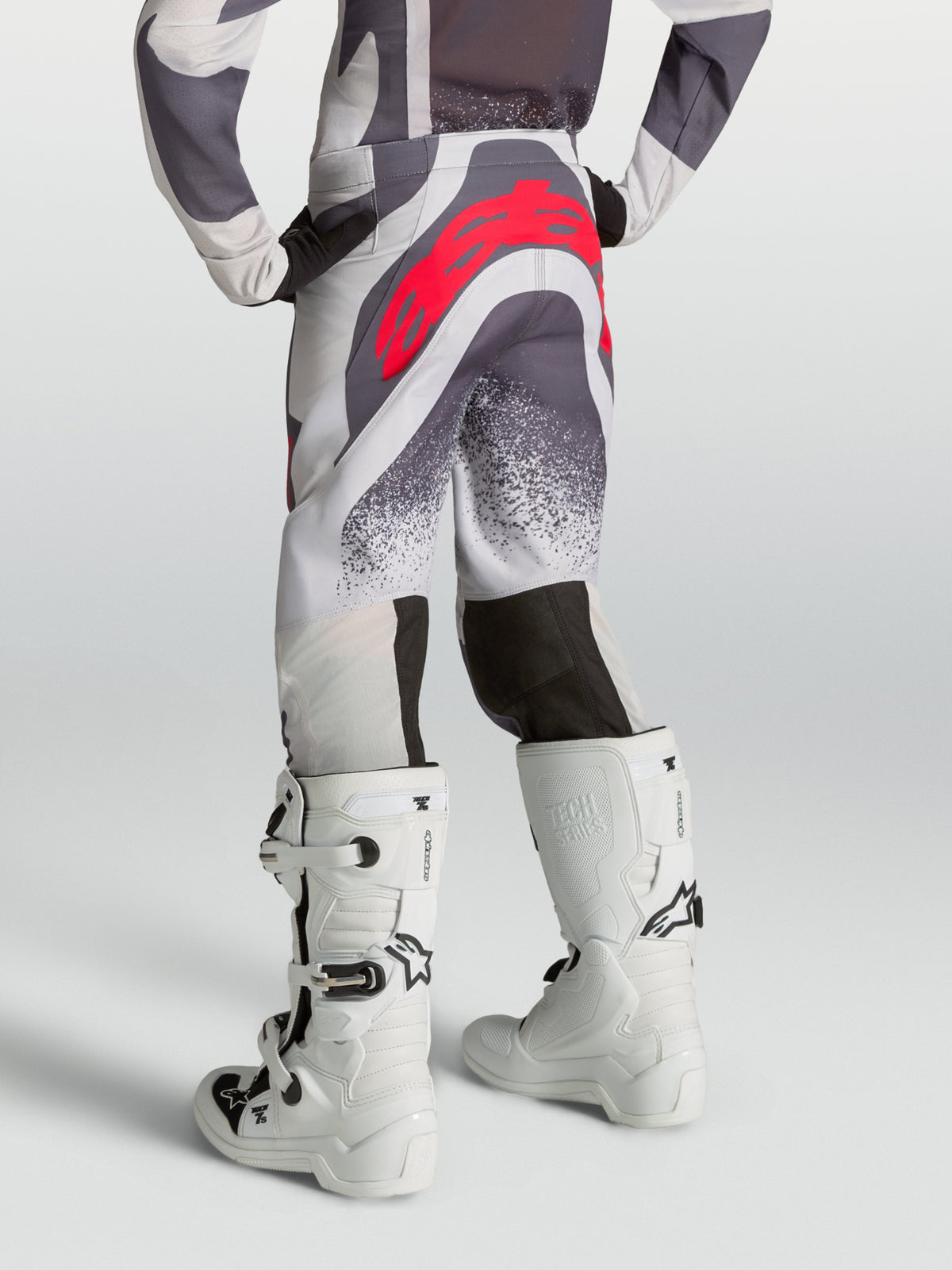 Alpinestars Pantaloni Supertech Swan Ragazzo, pantaloni motocross grigi e bianchi con logo rosso, vista posteriore su modello.