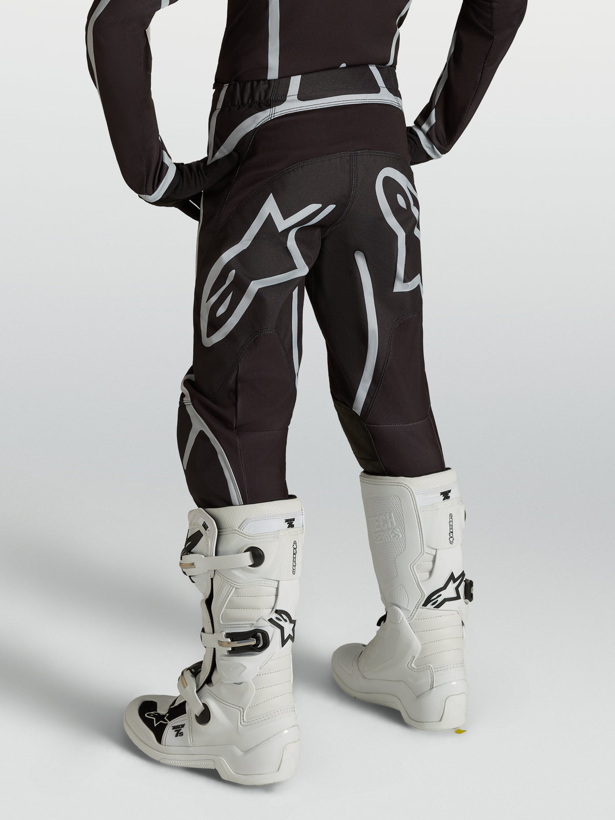 Alpinestars pantaloni Fluid Apex V2 ragazzo, motocross neri e argento, vista posteriore con stivali bianchi