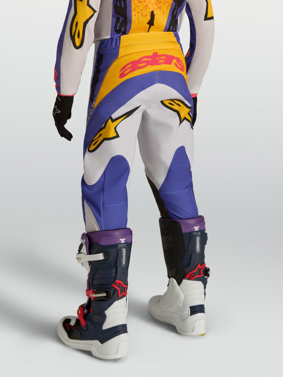 Alpinestars Pantaloni Fluid Drag Ragazzo, pantaloni da motocross blu e bianchi con grafica gialla, vista posteriore, costruzione ergonomica in poliestere 600D per off-road