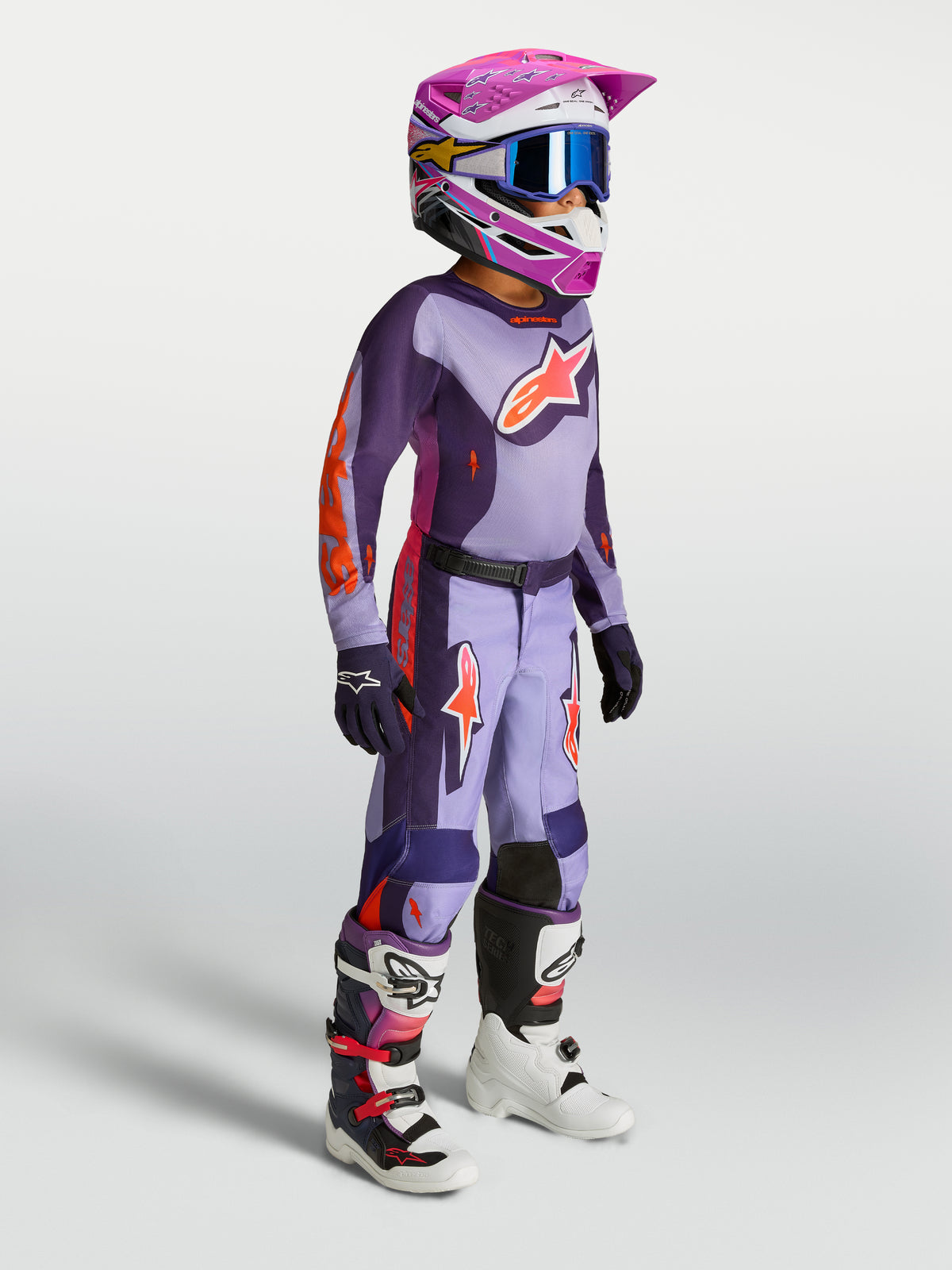 Alpinestars Pantaloni Fluid Hunt Ragazzo, set da motocross viola e arancione per giovani piloti con casco e stivali.