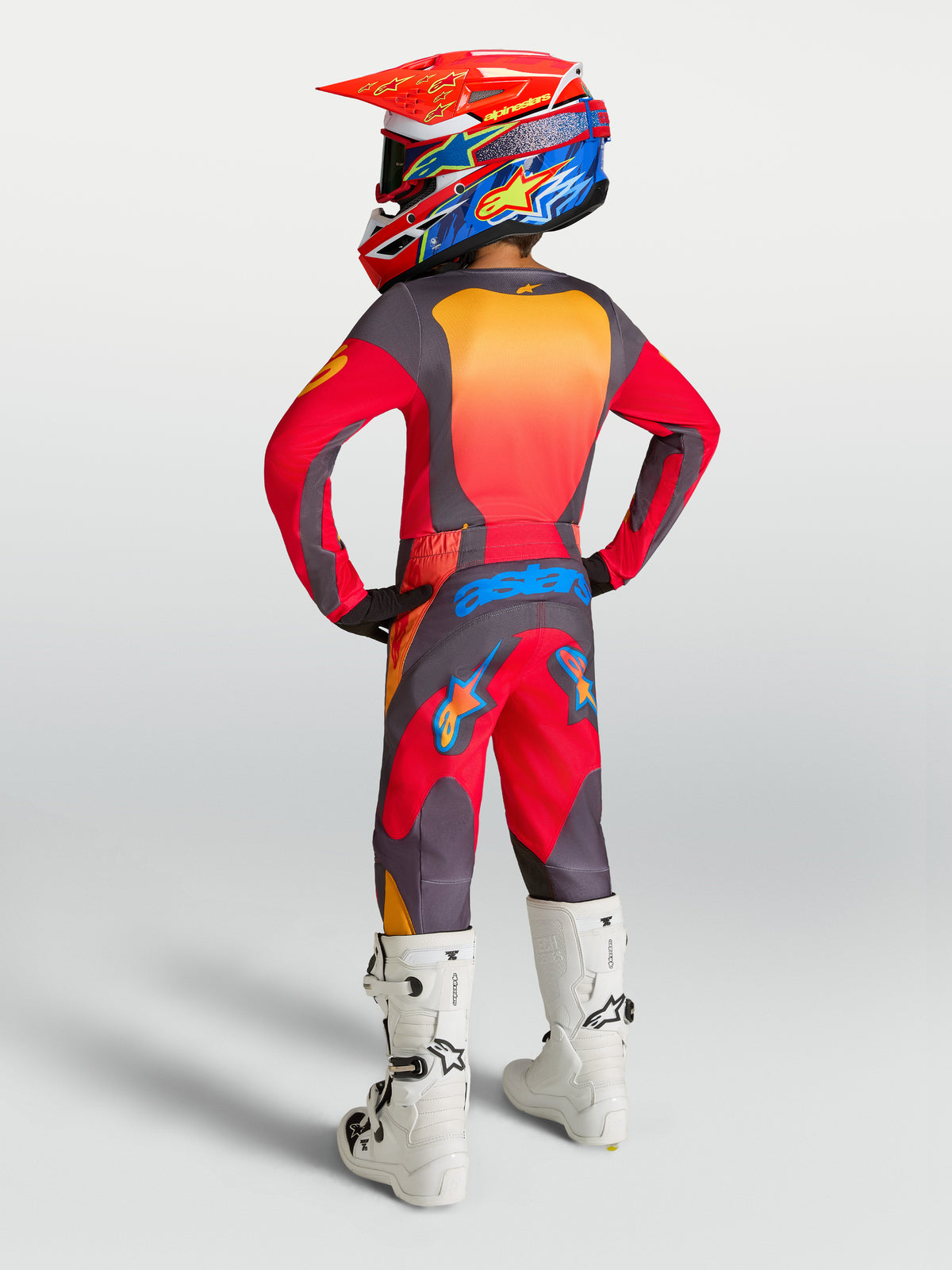 Alpinestars Pantaloni Fluid Hunt Ragazzo 2027, pantaloni da motocross per ragazzi, rosso fuoco e grigio, vista posteriore con completo off-road e stivali bianchi