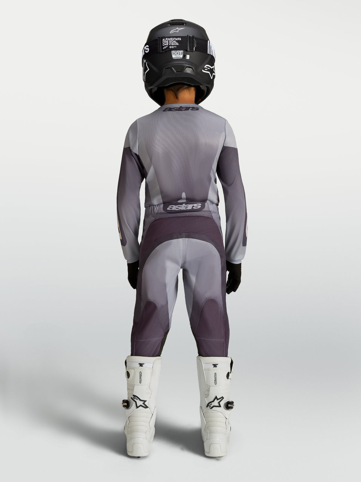 Alpinestars Pantaloni Fluid Amber Ragazzo 2027, pantaloni da motocross per ragazzi, grigio e sabbia, vista posteriore su un pilota, abbigliamento fuoristrada resistente e protettivo.