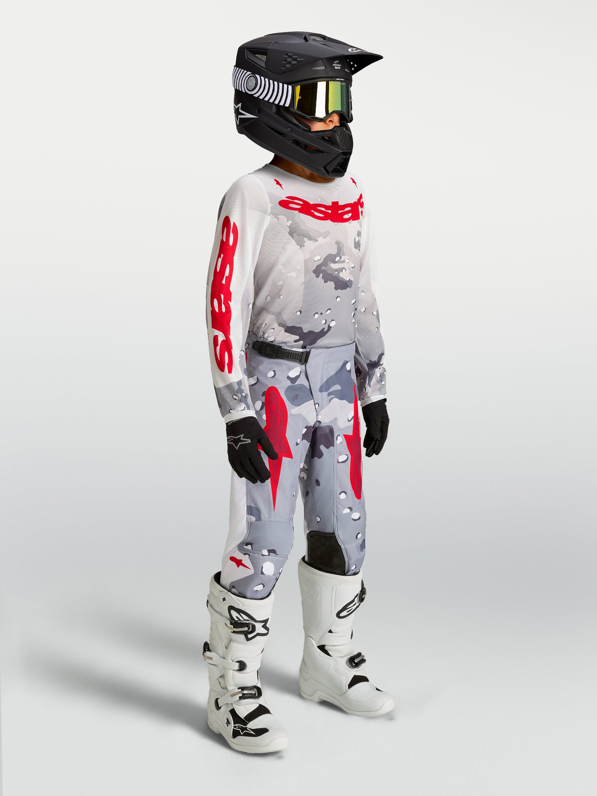 Alpinestars Pantaloni Fluid Lone Ragazzo, pantaloni da motocross racing, grigio mimetico e rosso fuoco, costruzione in tessuto 600D con taglio ergonomico, indossati da un giovane pilota