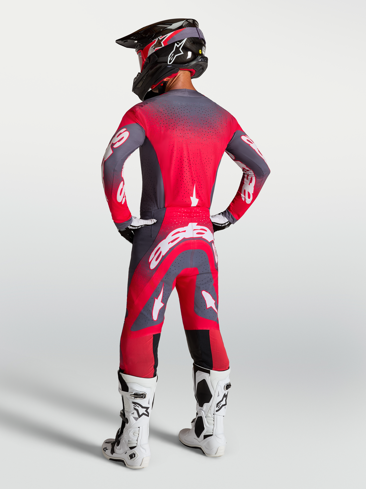 Alpinestars Maglia e Gear Set Supertech Hiten AFD, completo da motocross rosso fluo e grigio, vista posteriore su modello.