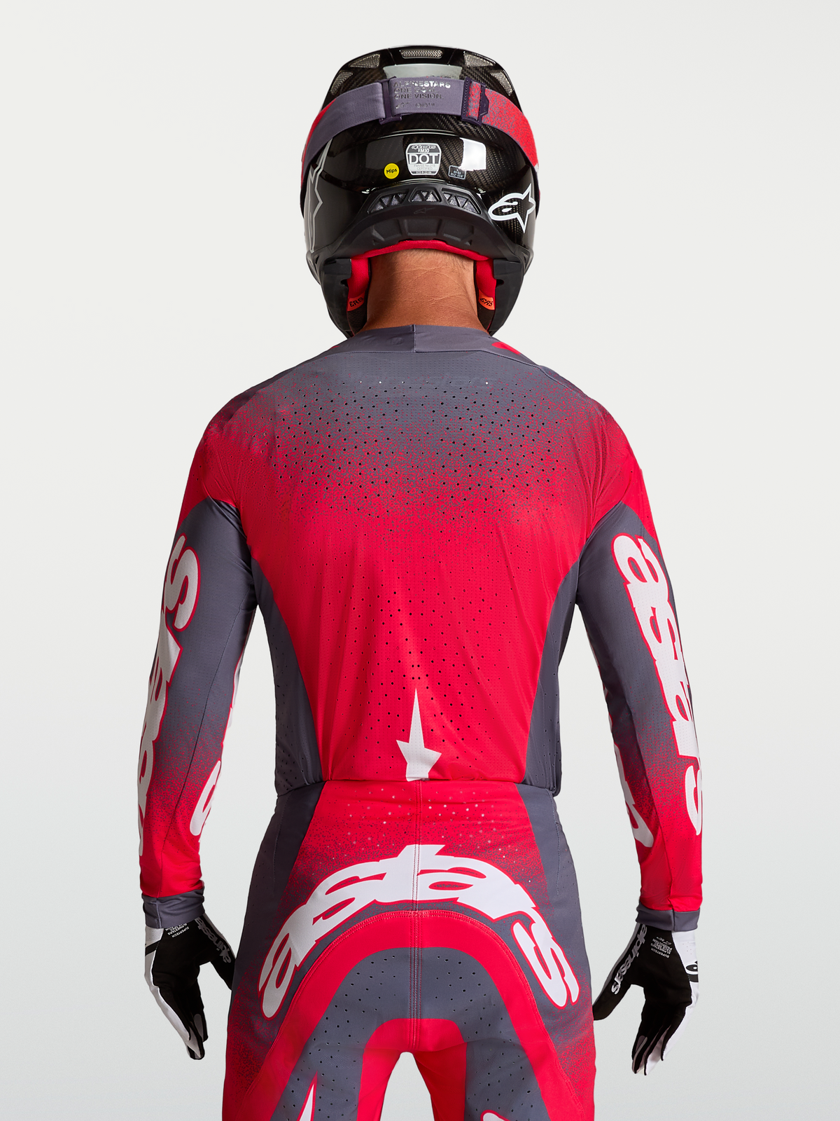 Alpinestars Maglia Supertech Hiten AFD, maglia da motocross per uomo, grigio e rosso fluo, costruzione in mesh ventilato con perforazioni laser-cut per un flusso d'aria ottimale, vista posteriore indossata da un pilota con casco e guanti, abbigliamento racing off-road