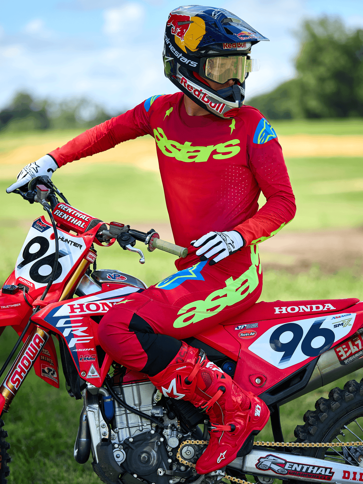 Pilota di motocross con maglia Alpinestars 2025 Supertech Maker, rosso brillante con marchio 'astars' giallo neon, indossata con pantaloni e stivali rossi coordinati, guanti bianchi e neri, seduto su una moto da corsa Honda rossa all'aperto