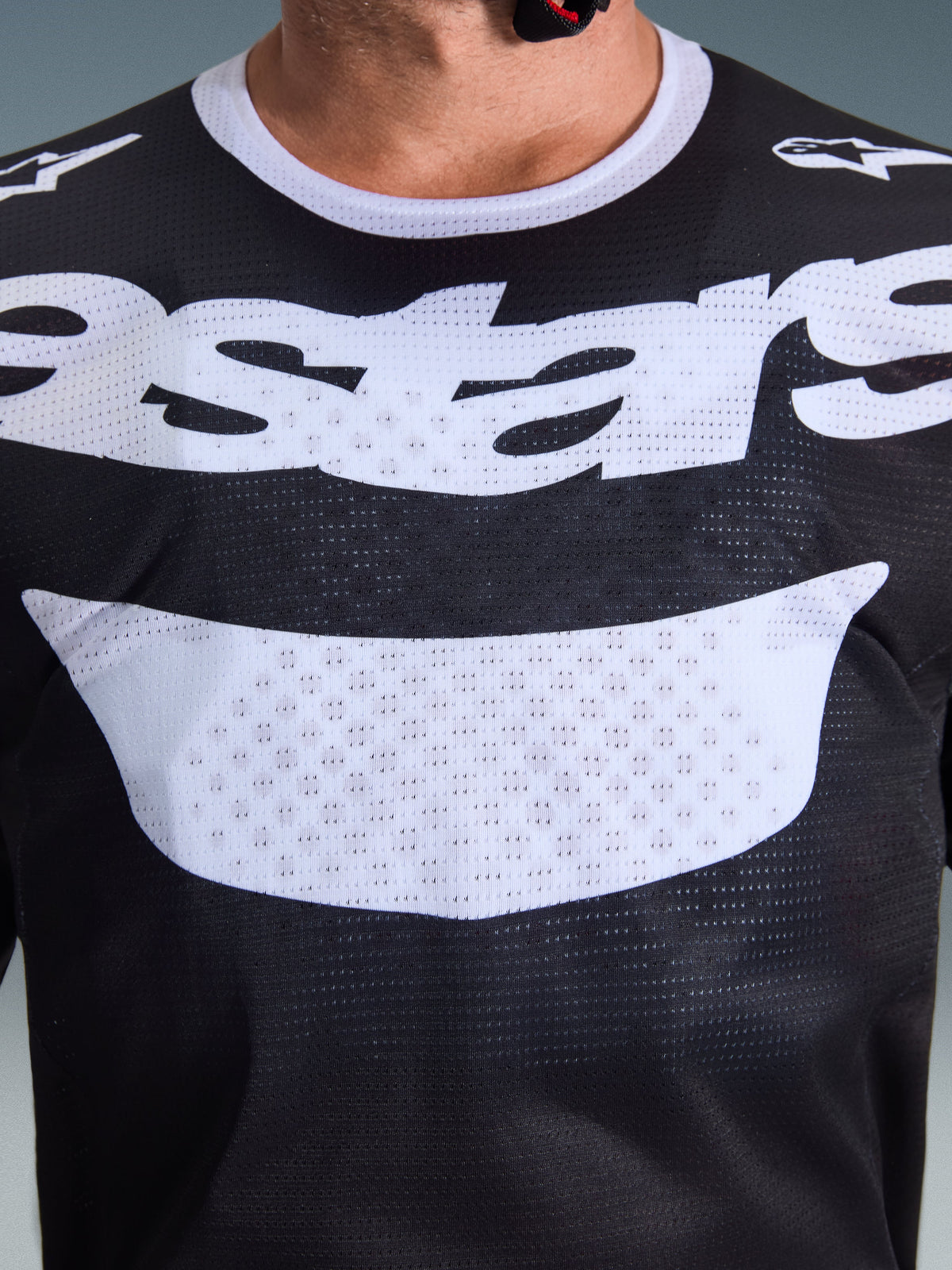 Alpinestars 2026 Racer Air Riway Jersey, maglia da motocross, nero e bianco, primo piano del torace che mostra la grande grafica bianca e la costruzione in mesh traspirante, colletto bianco e loghi sulle spalle