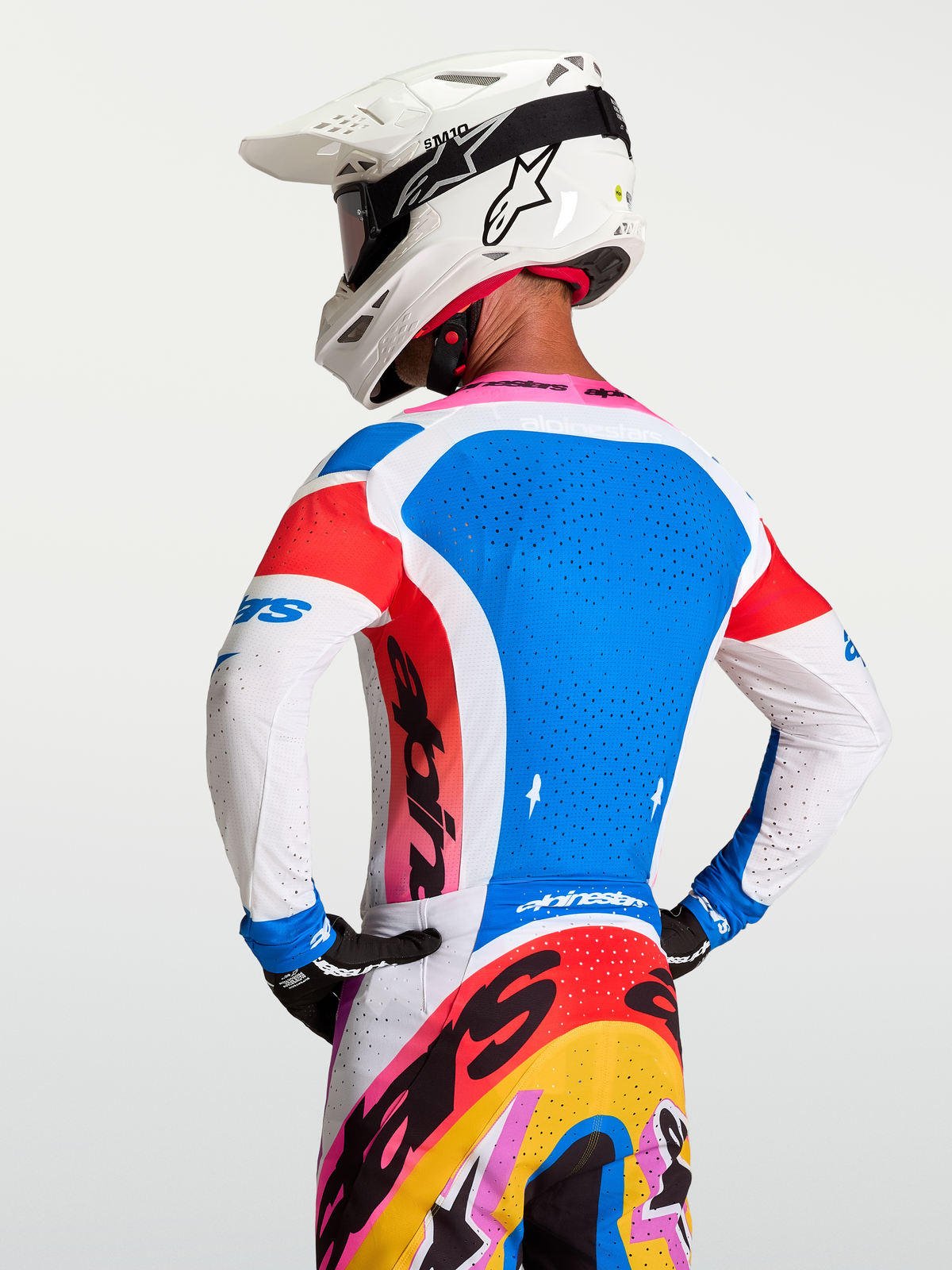 Alpinestars Maglia Supertech Dyna, maglia da motocross per uomo, blu e bianca, vista posteriore su modello con casco, mesh elasticizzata e fori di ventilazione laser.