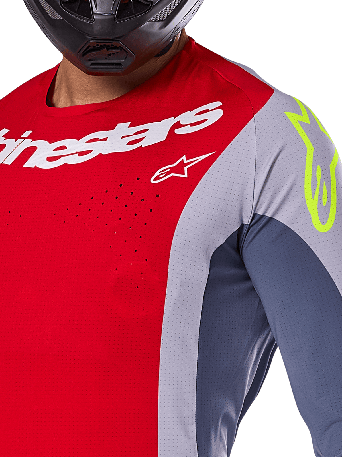 Maglia Alpinestars Techstar Melt 2025, maglia da motocross, rosso acceso e grigio con pannelli blu scuro, con marchio Alpinestars bianco e logo giallo neon sulla spalla, primo piano con perforazioni laser per la ventilazione e casco nero.