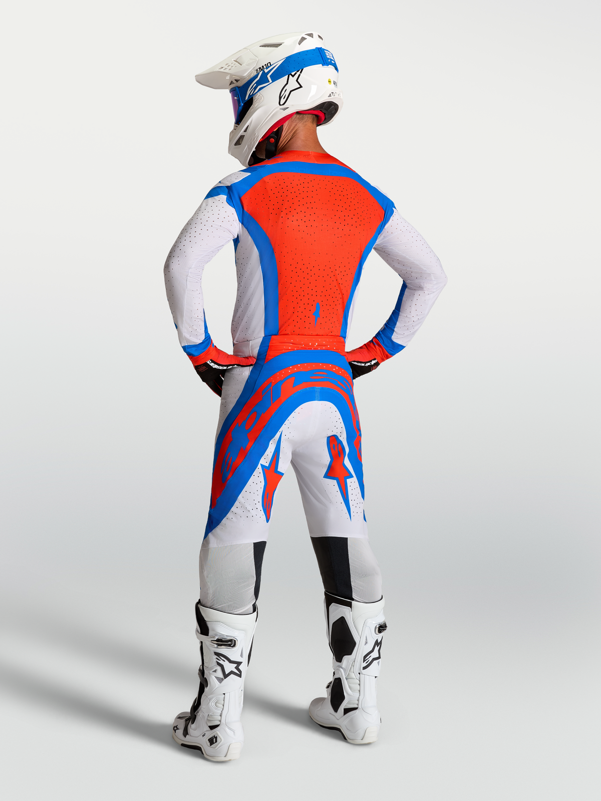 Alpinestars Supertech Vesta, completo da motocross per uomo, lilla chiaro e rosso cardinale, vista posteriore con casco e stivali coordinati.