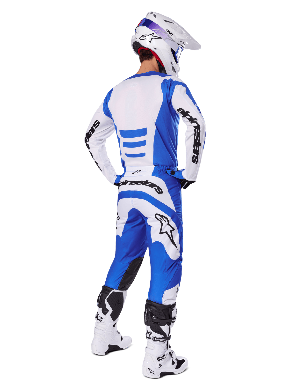 Pilota di motocross di spalle con completo Alpinestars 2025 Fluid Haul, maglia blu e bianca con pantaloni coordinati, casco bianco con dettagli blu e stivali da corsa bianchi e neri, abbigliamento da gara fuoristrada coordinato